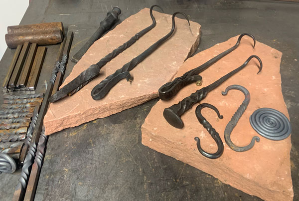 a variety of hand forged objects like meat flippers and hooks=